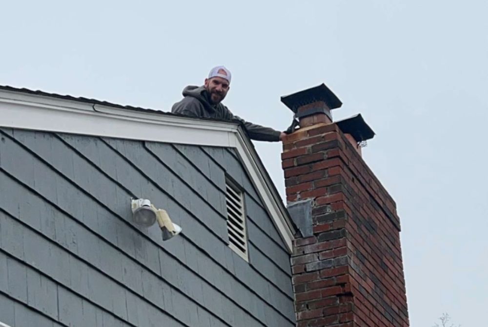 Dom Schiarizzi mason on top of roof repairing brick chimney